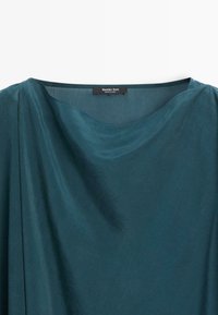 Satinbluse in Petrol mit weitem Rundhals und einem Massimo Dutti-Label am hinteren Kragen.
