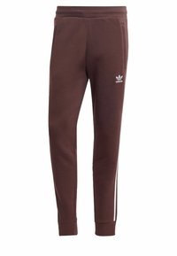 Pantaloni della tuta marroni a gamba affusolata con strisce laterali bianche, logo sulla parte superiore della gamba sinistra, vita elastica e tasche laterali. Realizzati in morbido tessuto.