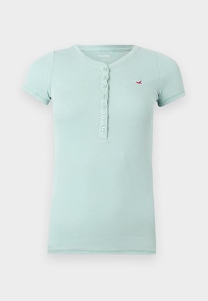 Ανοιχτό μπλε ριπ κοντομάνικο πουκάμισο με επτά κουμπιά και μικρό κόκκινο λογότυπο γλάρου στο αριστερό στήθος.