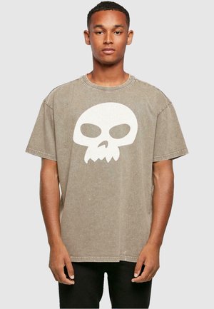 Brun oversized bomulds t-shirt med et stort hvidt kraniegrafik. Har rund hals og korte ærmer, med en falmet tekstur.