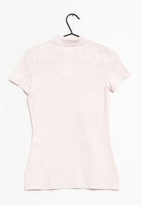 Różowa koszulka polo z kołnierzykiem i krótkimi rękawami, charakteryzująca się gładką teksturą i dopasowanym krojem, wyeksponowana na czarnym wieszaku.