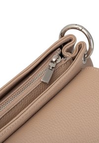 Borsa a mano in pelle beige con superficie texturizzata, dotata di chiusura a zip e anello in metallo argentato sulla parte superiore per attacco o trasporto.