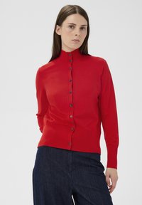 Cardigan roșu tricotat cu guler înalt, prevăzut cu nasturi pe față și mâneci lungi. Textură netedă cu nasturi întunecați contrastanți.