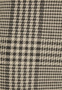 Black and beige woven fabric featuring a houndstooth pattern with varying scales, creating a textured visual contrast throughout.