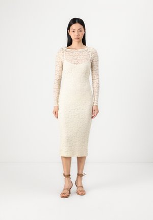 Rochie din dantelă cu mâneci lungi, de culoare crem, design ajustat, model floral, lungime până la jumătatea gambei, asortată cu sandale bej cu curele.
