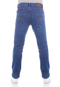 Jeans in denim blu con un design a gamba dritta, cinque tasche e un accento in pelle marrone sulla cintura. Le calzature sono sneakers bianche.