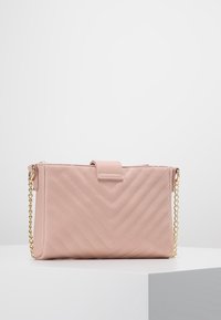 Borsa trapuntata rosa con motivo a chevron, realizzata in materiale sintetico. Presenta una chiusura con patta e una tracolla a catena dorata. Forma rettangolare compatta.