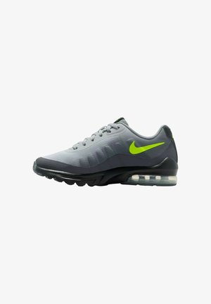 Zapatilla deportiva gris con parte superior de malla, collar acolchado y detalles en verde neón. Cuenta con una suela visible de aire y una suela exterior de goma texturizada.