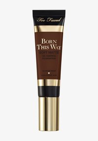 Brown tube foundation with gold and black accents, labeled "Born This Way Soft Matte." Features a pump dispenser, highlighting hyaluronic acid.