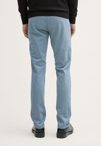 Lichtblauwe op maat gemaakte broek van een gestructureerde stof, rechtvallende snit, met een omgeslagen zoom, gecombineerd met zwarte schoenen.
