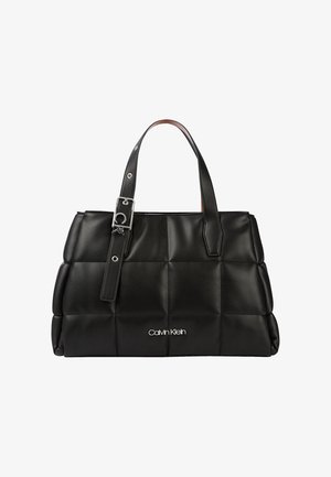 Sac à main en cuir noir matelassé avec deux anses, détail boucle argentée et logo Calvin Klein blanc centré sur le devant.