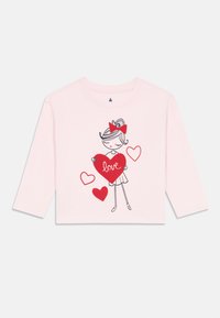 Light pink long-sleeve shirt with cartoon girl holding a large red heart labeled "love" and three smaller red hearts around her.