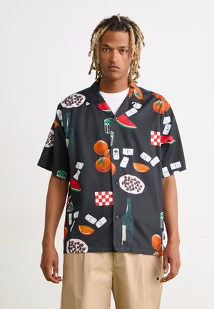 Camisa de manga corta negra con patrones vibrantes de comida y bebida, que incluyen tomates, sandía y diseños de cuadros. Tejido ligero.