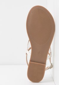 Beige sandaali, millel on tekstureeritud tald, avatud varvas ja õhukesed pahkluu rihmad. Suurus on taldadel märgitud 37, disain on lihtne.