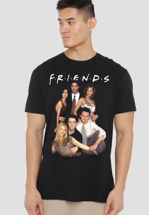 Mann trägt schwarzes T-Shirt mit buntem "FRIENDS"-Text und sechs Charakteren aus der TV-Show, die vorne gemeinsam posieren.
