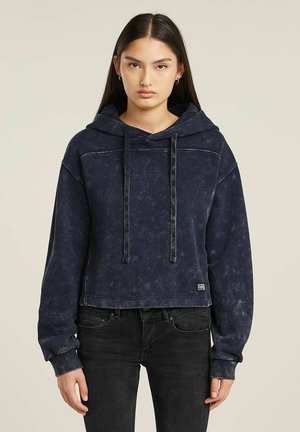 Sweat à capuche raccourci en bleu marine avec une finition vieillie, doté d'une capuche avec cordon de serrage, de manches longues et de poignets en côtes. Étiquette logo simple à l'ourlet.