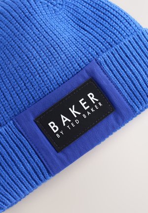 Modra pletena kapa z teksturiranim vzorcem, s trakom v čisti modri barvi in pravokotno črno nalepko z napisom "BAKER by TED BAKER."