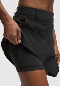 Falda deportiva negra con capa interior ajustada, que presenta un diseño plisado en la parte delantera y una cinturilla elástica. Tela suave y ligera con detalles cosidos.