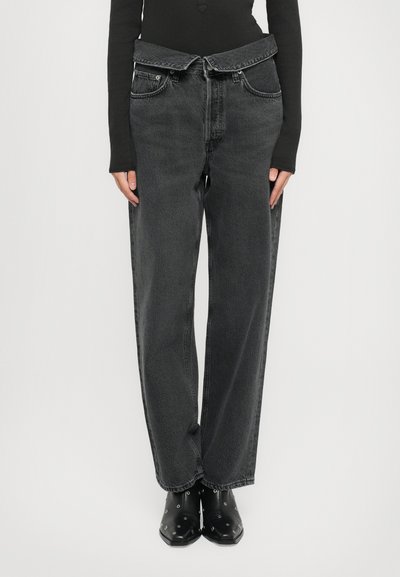 High-waisted black denim jeans with a loose fit, featuring a unique belted design and two front pockets. Soft texture with subtle fading.