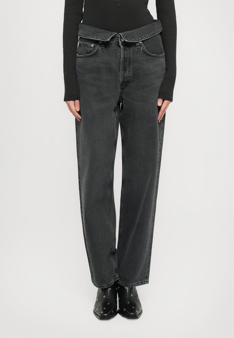 High-waisted black denim jeans with a loose fit, featuring a unique belted design and two front pockets. Soft texture with subtle fading.