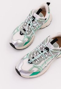 Sneaker argentate e verde menta realizzate in mesh e pelle, con lacci azzurri chiari, dettagli neri e una suola spessa.