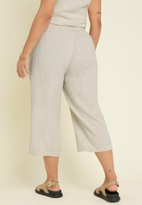 Ljusbeige capribyxor i en linblandning med resårmidja. Matchas med bruna sandaler som har en enkel design och textur.