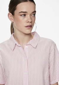 Camicia a maniche corte con colletto realizzata in tessuto leggero, caratterizzata da righe rosa e bianche, con bottoni sul davanti e una vestibilità rilassata.