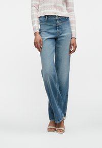 Ανοιχτό μπλε, φαρδιά τζιν παντελόνια με ψηλή μέση και διακριτική φθορά. Ενισχυμένες ραφές, κλασικός σχεδιασμός πέντε τσεπών και λεπτομέρειες με ξέφτια στο τελείωμα.