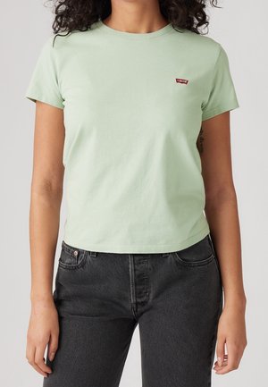 Jasnozielona bawełniana koszulka z krótkim rękawem i okrągłym dekoltem, z małym czerwonym logo Levi's na piersi. Zestawiona z ciemnymi dżinsami.