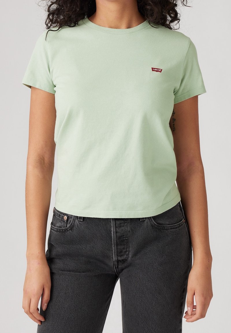 T-shirt en coton vert clair à manches courtes et col rond, avec un petit logo rouge Levi's sur la poitrine. Assorti à un jean sombre.