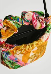Färgglad plisserad handväska med ett vridet tyghandtag, svart inredning och en strukturerad form med olika livfulla nyanser och mönster.