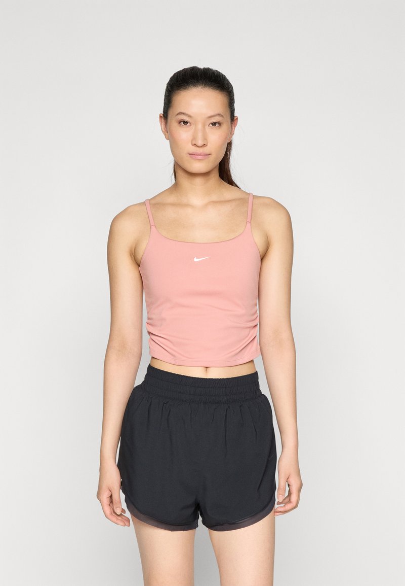 Rosa, kort tanktop med tynne stropper og en hvit logo, kombinert med svarte shorts med elastisk midje og en subtil glans.