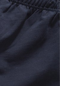 Tamno plavi materijal, spoj pamuka, blago teksturiran s mekanom, glatkom površinom. Elastična waistband na vrhu. Bez uzoraka ili dodatnih detalja.