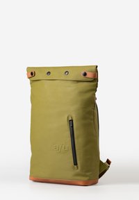 Olijfgroene roll-top rugzak met zwarte hardware, een voorvak met rits en een basis van bruin leder. Bevat een reliëflogo en drukknoopsluitingen.