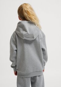 Grauer Kapuzenpullover aus weichem Material, mit lässigem Schnitt, überschnittenen Schultern und gerippten Bündchen und Saum.