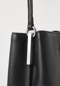 Borsa a tracolla in pelle nera con texture liscia, hardware argentato e design elegante. Include una tracolla regolabile e un'etichetta con il marchio.