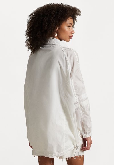 Weiße, leichte Jacke mit lockerer Passform, transparenten Ärmeln, elastischen Bündchen und Kordelzug am Saum. Mit fransigen Kanten und seitlichen Streifen.