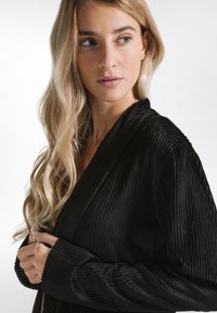 Cappotto avvolgente in tessuto a righe nere con maniche lunghe e scollo a V profondo, caratterizzato da una texture morbida e un design minimalista.
