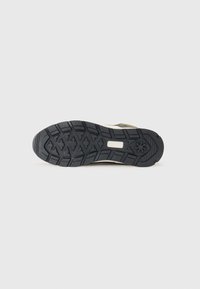 Black rubber outsole with textured tread pattern, featuring deep grooves and a rectangular cutout in the arch area for support.