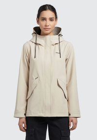 Ljust beige vattentät jacka med huva, med justerbara dragsnören, två framfickor och ett märkeslogotyp på bröstet.