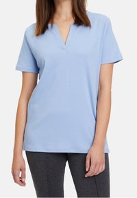 Světle modrá košile s krátkým rukávem a V výstřihem, uvolněného střihu, vyrobená z měkkého materiálu. Jednoduchý design, bez vzorů nebo ozdob.