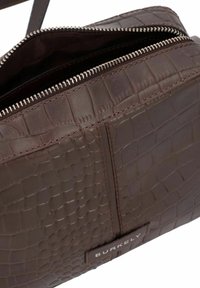 Borsa in pelle marrone con stampa a effetto coccodrillo, dotata di chiusura con zip, caratterizzata da accessori in argento, cuciture sottili e un'etichetta con il nome del marchio.