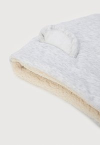 Ανοιχτό γκρι μωρουδιακό γάντι με μαλακή κρέμα-χρωματιστή επένδυση από fleece και μικρή στρογγυλή λεπτομέρεια από ύφασμα στην κορυφή, παρουσιασμένο σε λευκό φόντο.