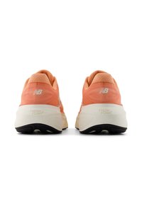 Lichtoranje sport schoenen met gestructureerde bovenkant, Fresh Foam demping en zwarte rubberen zolen, met een wit logo op de hiel.