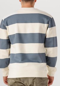 Sweatshirt rayé crème et bleu avec des manches longues, un col rond et des poignets côtelés. Tissu doux et texturé avec une coupe décontractée.