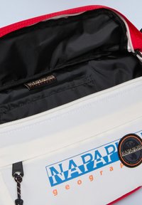 Bolsa blanca y roja con un interior negro, que cuenta con un parche de logo, cierre con cremallera y un bolsillo interior con una pestaña. Tejido duradero.