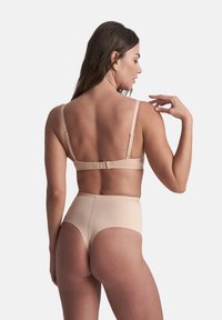 Beige underkläder i ett set med en mjuk, elastisk tyg. Bh:n har justerbara band och en knäppning; de högmidjade trosorna är sömlösa.