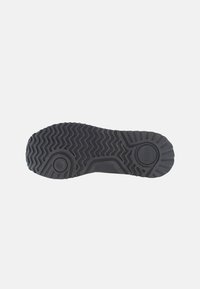 Suola di scarpa in gomma nera con un motivo a zigzag testurizzato per la presa, con accenti circolari e un logo posizionato centralmente.