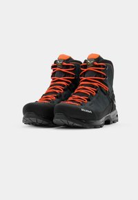 Black hiking boots with orange laces, sturdy rubber soles, and textured fabric upper; features reinforced toe and heel for durability.