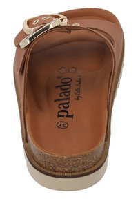 Braune Slippersandale mit Korkfußbett, strukturiertem Obermaterial und einem metallischen Schnallenakzent. Mit beigem Außensohlen und gedrucktem Logo innen.